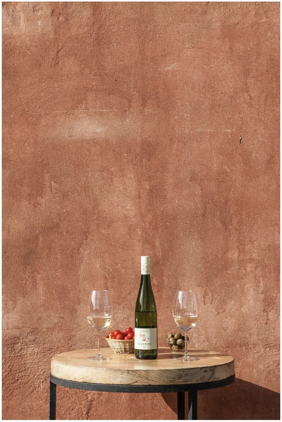 Wine, glasses and Sicilian produce against a terracotta wall